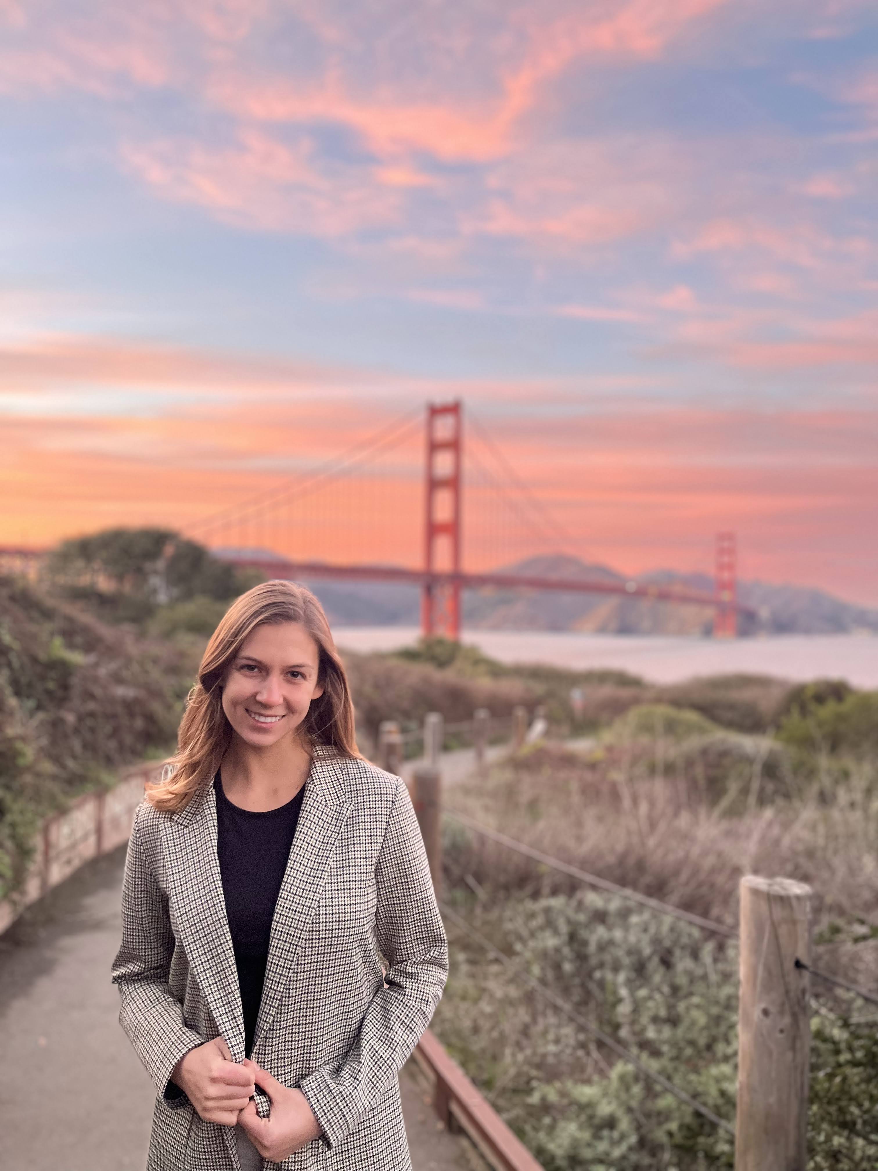 Claire in the Presidio at sunset, with the Golden Gate behind her.