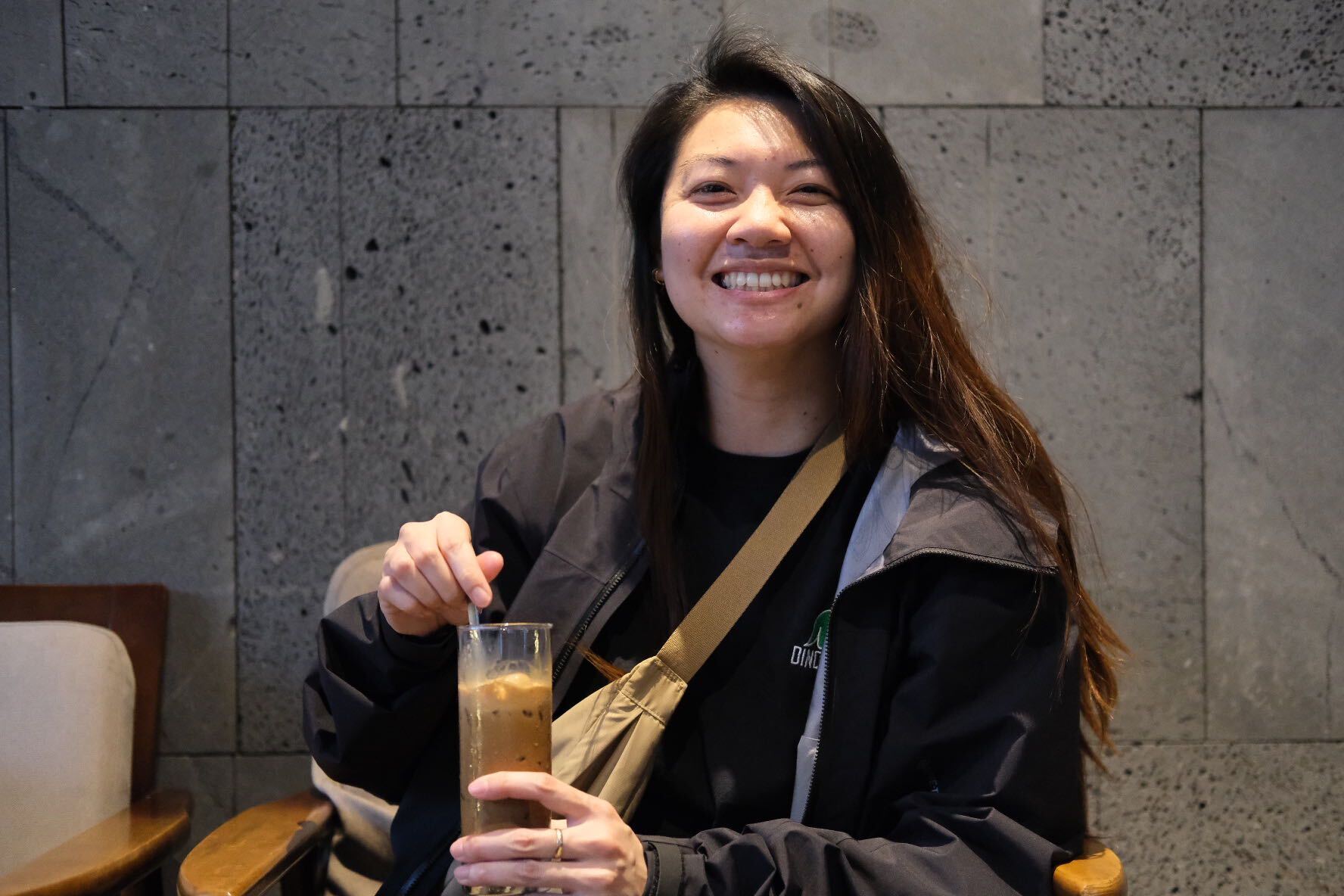 Jenny smiling and enjoying an iced coffee.