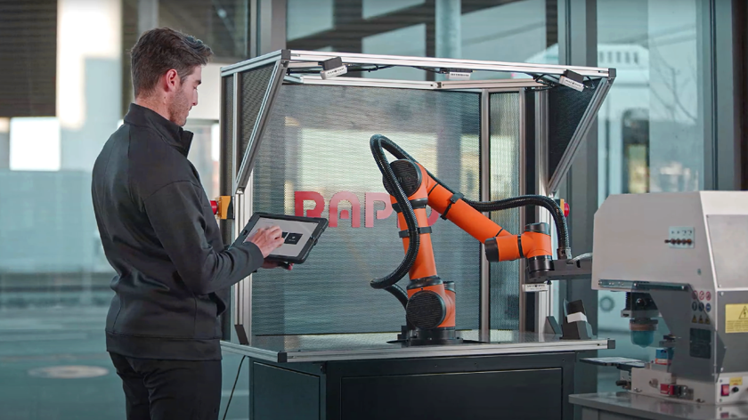 An engineer programs a cobot arm with a touchscreen interface.